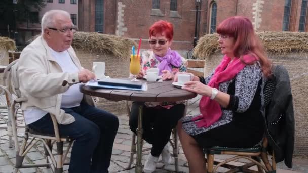 Les retraités parlent assis à table avec des boissons savoureuses dans un café — Video