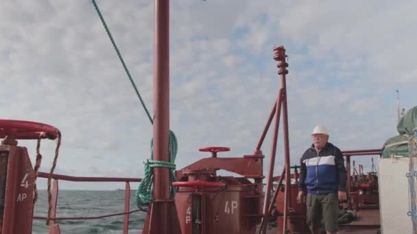 Senior-Kameramann mit weißem Helm läuft Tankschiff entlang — Stockvideo