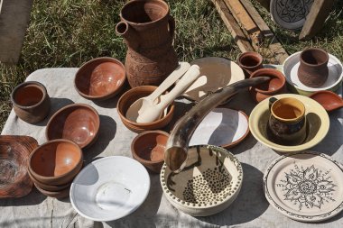 Masada olan mutfak eşyaları kupalar, bardak, kaşık, kase, kil levha, yazma, seramik bir sürahi bir boynuz