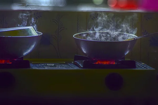 Fume or the vapor of boiling water during the cooking on Gas oven from two utensils. India. 2019.