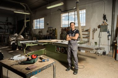 İşçi fabrikada kameraya bakıp gülümsüyor. Uzun atış, tüm vücut..