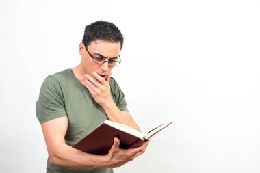 Gözlüklü bir adam, kitap okumaya çok odaklanmış. Orta atış. Beyaz arkaplan.