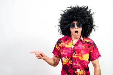 Afro peruklu, güneş gözlüklü ve Hawai gömlekli bir adam, çok şaşırmış görünüyor. Orta atış. Beyaz arkaplan.