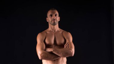 Gömleği olmayan atletik bir adam. Orta atış. Siyah arkaplan.