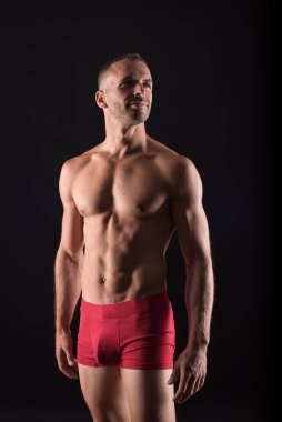 İç çamaşırlı atletik bir adam. Orta atış. Siyah arkaplan.