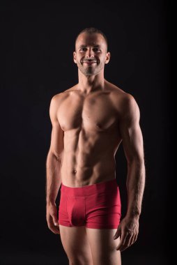 İç çamaşırlı atletik bir adam. Orta atış. Siyah arkaplan.