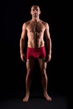 İç çamaşırlı atletik bir adam. Tam vücut. Siyah arkaplan.