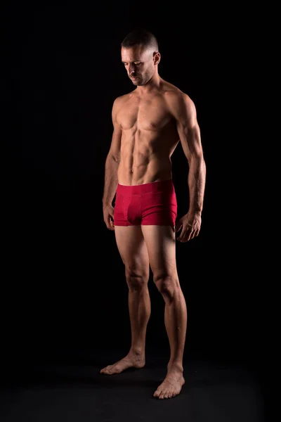 İç çamaşırlı atletik bir adam. Tam vücut. Siyah arkaplan.