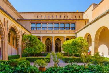 Zaragoza, İspanya, 11 Mayıs 2024. Aljaferia Sarayı. Süslü kemerler ve yemyeşil ağaçlar Santa İsabel terası çerçevesi
