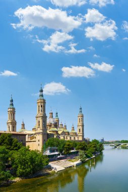 İspanya, Zaragoza 'da beyaz bulutlu mavi gökyüzünün altındaki Ebro Nehri' ni yansıtan bazilika del Pilar manzarası