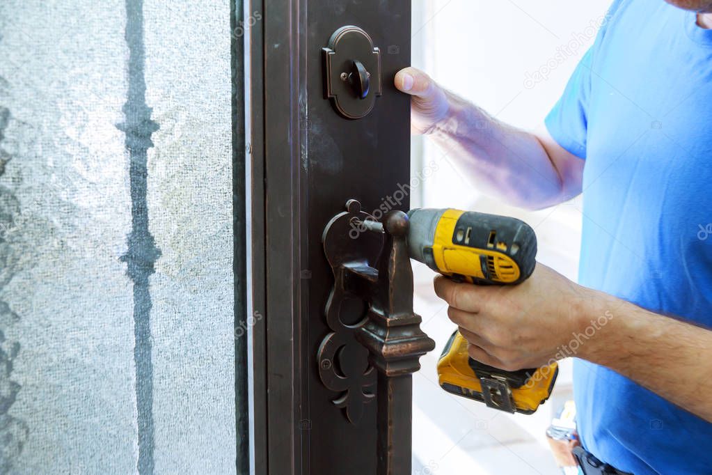 Male handyman carpenter at interior metal door lock installation using screwdriver,
