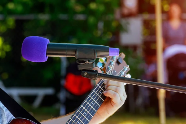 Musicien masculin jouant de la guitare acoustique derrière le microphone à condensateur dans l'enregistrement — Photo