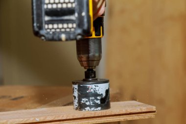 Bir pil kullanan bir adam bir ahşap tahta bir delik matkap bit matkap desteklenmektedir. Delme ahşap tahta