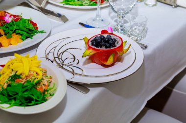 Red Dragon meyve suyu bir çanak saman içinde çiçekli kumaş üzerinde Plumeria çiçeklerle süslenmiş. Üstten görünüm.