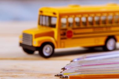 Renkli kalemler ve oyuncak sarı okul otobüsü ahşap zemin üzerine okula dönüş sağlar