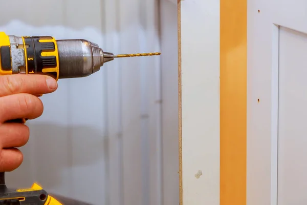 Installation of furniture hinges on the cabinet door master drills the door in the cabinet door