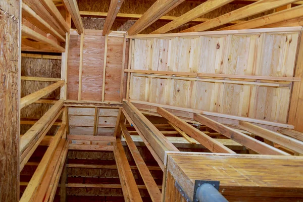 Interior of a new home under construction, with stairs to an opening for wooden beams at construction