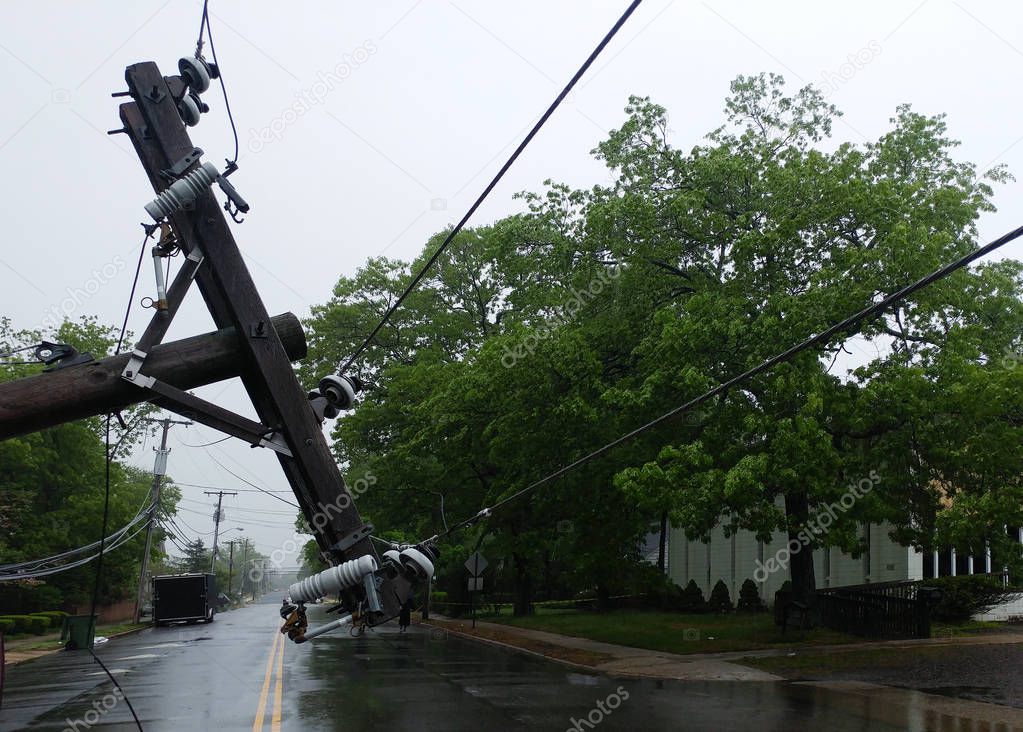 The storm caused severe damage to electric poles power lines over a road after Hurricanepoles falling tilt.