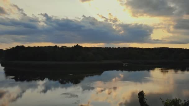 Paisagem colorida de rio perto de uma floresta sob um belo céu com nuvens brilhantes durante o pôr do sol — Vídeo de Stock