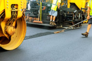 Yol silindiri bir yol inşaat sahasında taze asfalt kaplama sırasında yol Döşeme fayans ustası