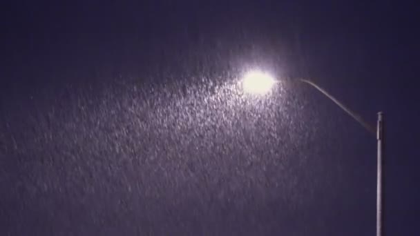 Flocos de neve cair contra o fundo da lâmpada de rua noite de inverno tiro na luz — Vídeo de Stock