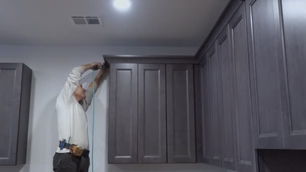 Handyman working instal brad nail gun to Crown Moulding wall cabinets framing trim — Stock Video