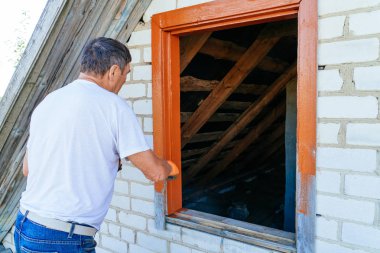 Adam etrafında döşeme boyalar bir ile fırça boyama ahşap pencere dış