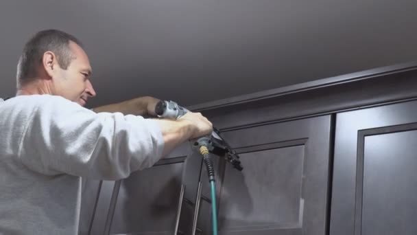 Brad çivi hava tabancası taç kalıplama için trim çerçeveleme beyaz mutfak duvar dolapları üzerinde kullanarak inşaat işçisi, — Stok video