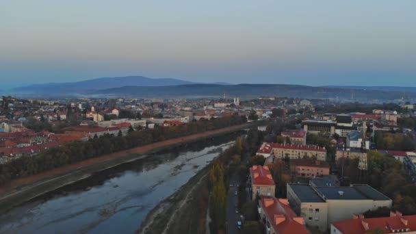Luchtfoto van middenklasse huizen in het kleine dorp of stad op het platteland. over de rivier de Uzh huizen bovenaanzicht bovenstaande bij zonsopgang Oezjhorod Oekraïne Europa — Stockvideo