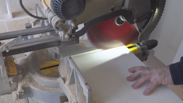Trabajador de la construcción que utiliza sierra de mitra de compuesto deslizante o sierra circular para cortar tablero de madera masiva . — Vídeos de Stock