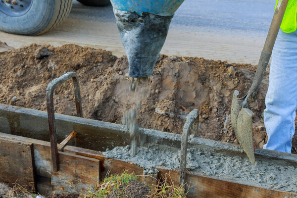 Работники каменной кладки заливают цемент во время модернизации жилой улицы
