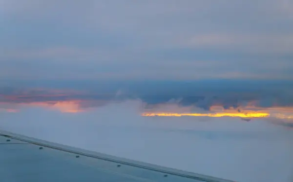 Clouds and sky as seen through window of an aircraft at sunset — Stock Photo, Image