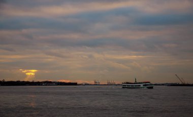Gün batımı ve Amerikan sembolü Özgürlük Anıtı, New York limanında Konteyner Vinç