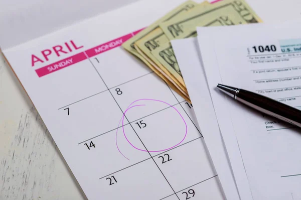 Calendar with words Tax Day , dollars and form 1040 income tax form showing tax day for April