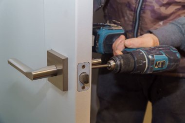 Kapı kolunu kilitle, Carpenter vidayı sıkıştır, elektrikli matkap tornavidayla, yakın çekim..