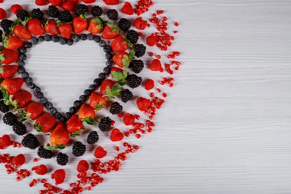 Collection of fresh fruits heart of berries on wooden background