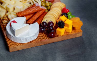 Muhtelif kraker, yeşil zeytin, peynir ve et fındık ile taze ahşap tahta kesme ve gri kurullarında çilek