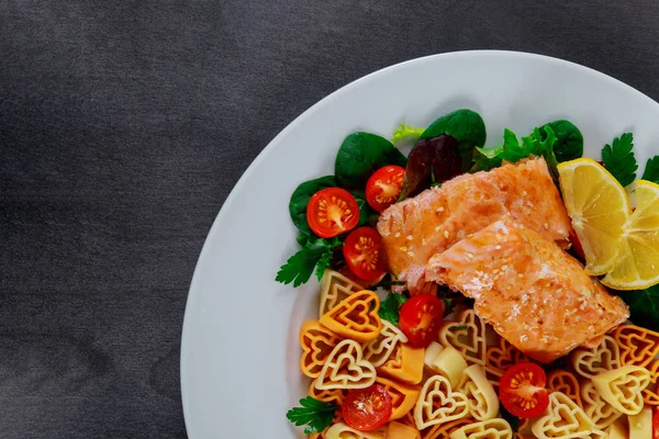 Pasta in the form of a heart salad with salmon and vegetables decorated with hearts Valentines Day.
