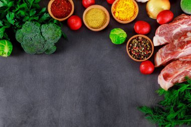 Çiğ et sulu biftek kavurma, çeşitli baharatlar, biber ve otlar için hazır. Bir kara tahta arka plan üzerinde metin için yer.