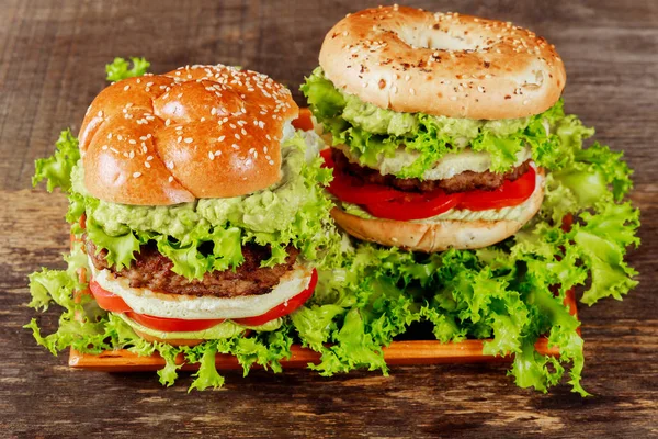 Guacamole beef burger with melted cheese and lettuce on wooden background