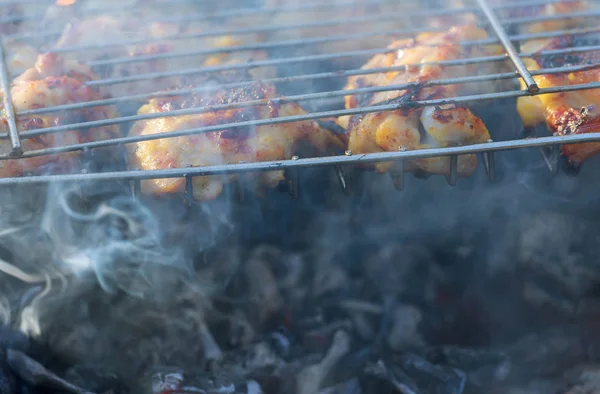 Patada de pollo a la parrilla sobre llamas en una barbacoa . — Foto de Stock