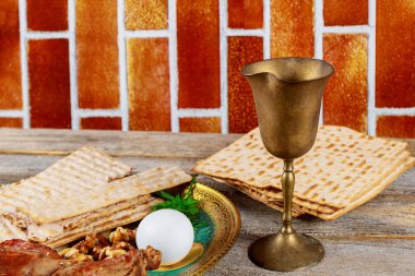 Jewish holiday Passover with wine and seder plate on matzoh, wooden table clipart
