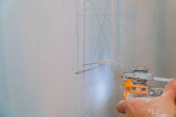 Человек режет гипсокартон ремонтными работами электроножа в реставрации помещений. Дриволновая панель . — стоковое фото