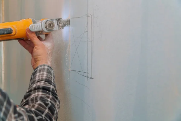 Construction worker cutting gypsum plasterboard by using electric cutter angle grinder Stock Photo