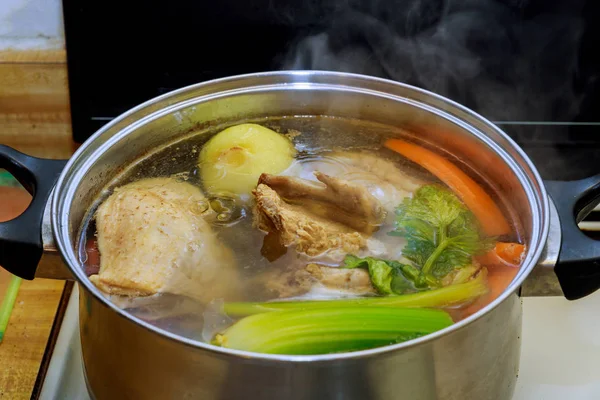 Caldo de galinha com pedaços de legumes em uma panela de metal antes de cozinhar com sopa de frango com legumes no processo de preparação — Fotografia de Stock