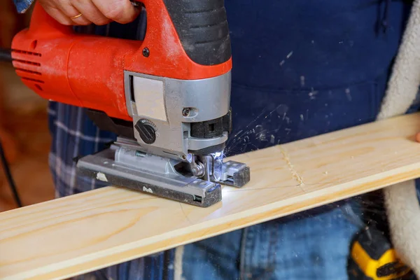 Man cutting a plank with a jigsaw machine sawing wood board — Stock Photo, Image