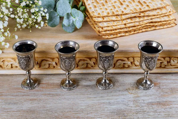 Páscoa matzoh pão feriado judaico, quatro copos kosher vinho sobre mesa de madeira . — Fotografia de Stock