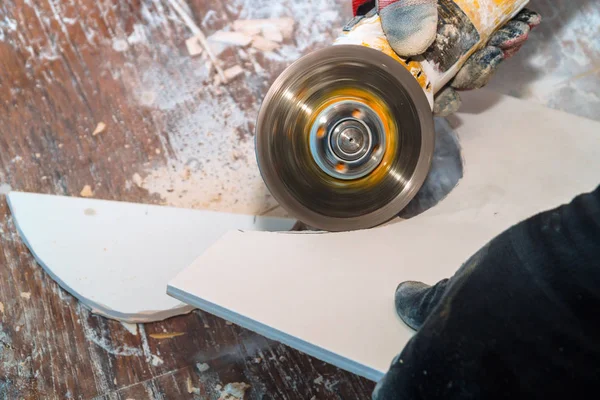 Працівник ріже плитку за допомогою шліфувальної машини, нарізаної шарами керамічної плитки для підлоги — стокове фото