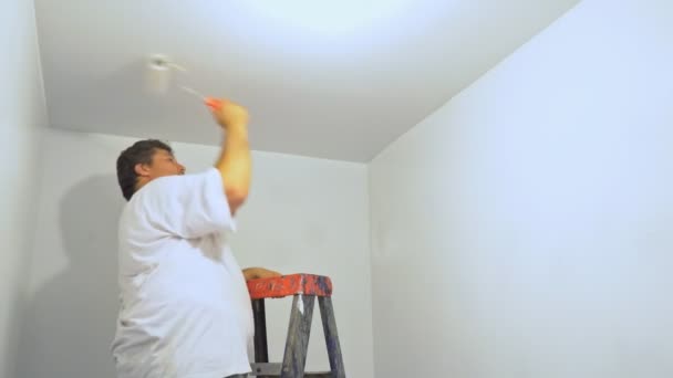 Pintor hombre en el trabajo con la pintura de rodillos escalera de techo en primer plano — Vídeos de Stock