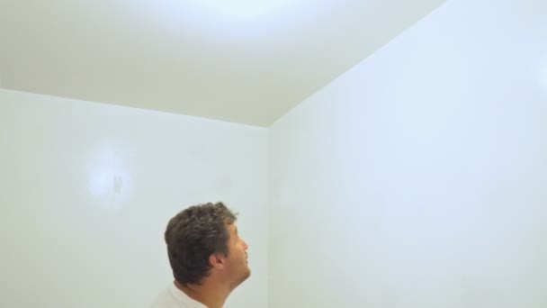 L'uomo usa pennello pittura sulla parete e soffitto per la ristrutturazione della casa . — Video Stock